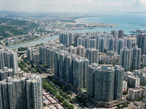 Elevated view of New Bordeaux with high-rise apartments, parks, busy boulevards, and diverse crowds near the coast.